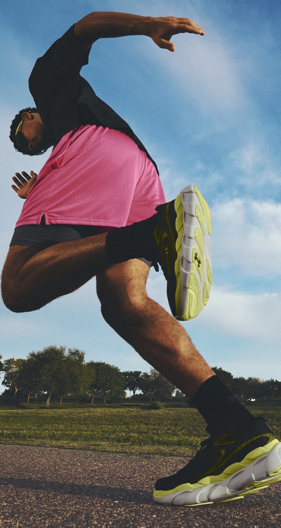 Runner mid-stride on a park path in UA HB Runner 2, Ultimate Black / Sonic Yellow
