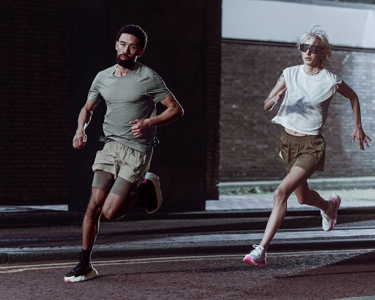Two runners on a city street at dusk in HB Run apparel and UA HB Runner 2